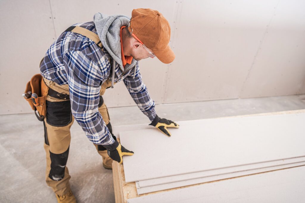 Construction Worker Preparing Building Materials. Drywall, Sheetrock and Plywood Boards. Construction Industry Theme.